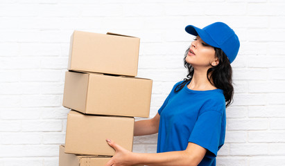 Young delivery woman over white brick wall