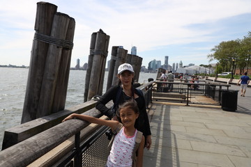A mother and her daughter pose with jersey city in background