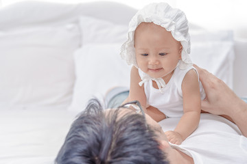 Lovely Asian little girl smiling with her father. Daddy holding and hug little baby on his body. Family having a happy time. Father's day concept.