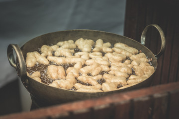 Fried dough in big pan for sell in morning market of Thailand.