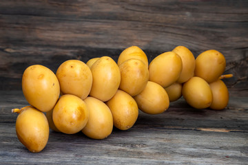Sprig of ripe yellow dates close-up on a wooden table