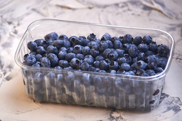 fresh and tasty Blueberries in a plastic can on old rustic wooden table