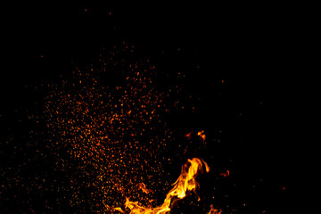 Fototapeta na wymiar Burning red hot sparks fly from large fire in the night sky. Beautiful abstract background on the theme of fire, light and life.