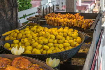 Potatoes and grilled shashlik are prepared on a market. Concept: food on vacation