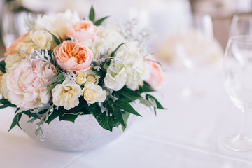 Fine wedding floral arrangement with pink peonies, white roses, dusty miller, and greenery, silver vase, white tablecloth, luxury wedding reception decor