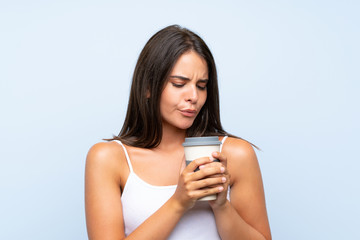 Young woman holding a take away coffee over isolated blue background