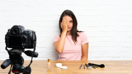 Young girl recording a video tutorial covering a eye by hand