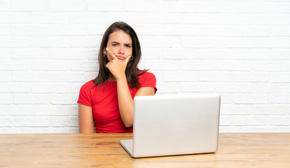 Young girl with pc in a table thinking an idea