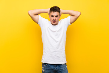 Young handsome man over isolated yellow background frustrated and takes hands on head