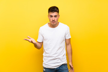 Young handsome man over isolated yellow background making doubts gesture