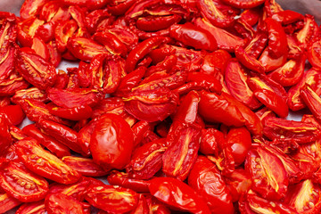 Homemade dried red  tomatoes slices with basil oregano spices cooking process. Traditional Italian Mediterranean kitchen cuisine.