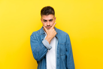 Young handsome man over isolated yellow background thinking an idea