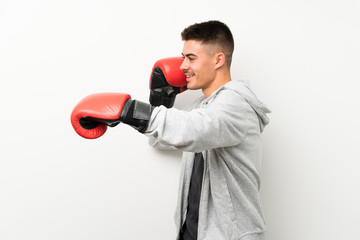 Sport man over isolated white wall with boxing gloves