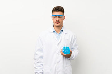 Young scientific holding laboratory flask over isolated background standing and looking to the side