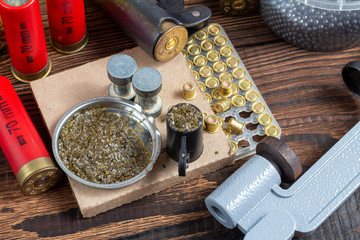 reloading process shotgun shells with special reload equipment. Powder, bullets, fraction, shells, buckshot on the wooden background