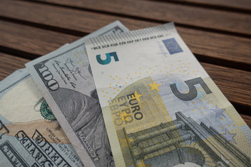 100 US Dollar versus 5 Euro concept on brown wooden tiles background.