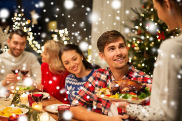 holidays and celebration concept - happy friends having christmas dinner at home over snow