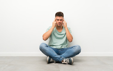 Young handsome man sitting on the floor unhappy and frustrated with something. Negative facial expression