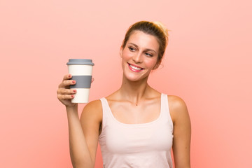 Young blonde woman holding a take away coffee with happy expression