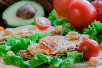Crispbread with hummus on vegetable background