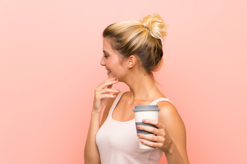 Young blonde woman holding a take away coffee thinking an idea and looking side