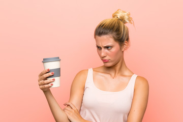 Young blonde woman holding a take away coffee with sad expression