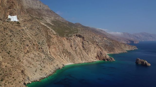 Aerial drone video of breathtaking whitewashed holy Monastery of Panagia Hozoviotissa built in a steep cliff overlooking the Aegean deep blue sea, Amorgos island, Cyclades, Greece