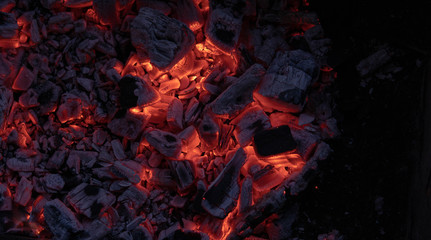 The texture of the coal fire. Actively smoldering embers of fire. Background of burning hot coals. Flicker of burning coals at night