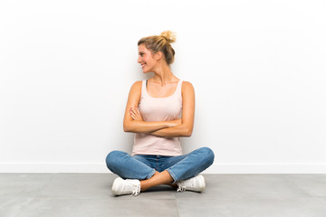 Fototapeta na wymiar Young blonde woman sitting on the floor laughing