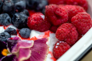 Vanilla ice cream dessert with fresh blueberries and raspberries. Close up top view. Tropical vacations concept.