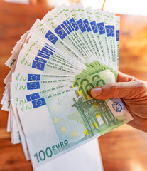 Mano di donna con un fascio di banconote da 100 euro, simbolo di ricchezza, soldi facili, guadagni online