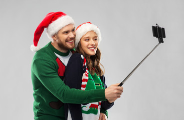 christmas, technology and holidays concept - happy couple in santa hats taking picture by...