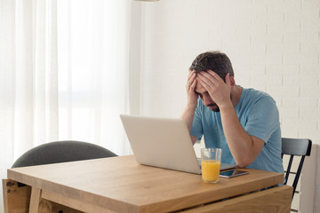 Young man disappointed while working on laptop.