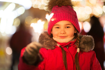 holidays, childhood and people concept - happy little girl with sparkler at christmas market in winter evening