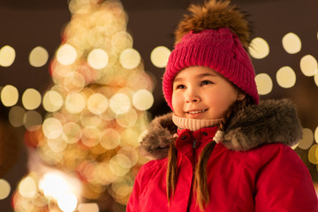 holidays, childhood and people concept - happy little girl at christmas market in winter evening