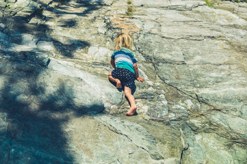 Little toddler climbing on rocks © LoloStock