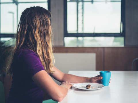 Young woman having breakfast and coffee in apartment