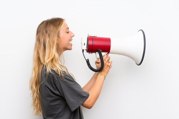 Blonde young woman over isolated white background shouting through a megaphone