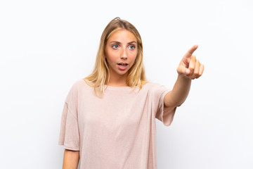 Fototapeta premium Blonde young woman over isolated white background pointing away