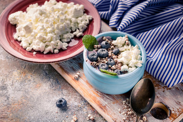 Close-up curd sweet dessert with fresh blueberries in blue deep bowl. Healty breakfast