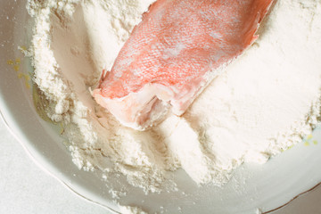 Fototapeta premium Fresh sea bass rolled in white flour for frying in pan.