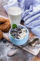 Cottage cheese with fresh blueberries, oatmeal cookies and milk. Healthy and tasty breakfast. Vertical shot