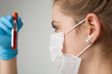 young woman with medical gloves and medical face mask holding a blood probe