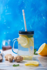Ginger Water in Glass jar With Lemon and Honey on Blue Background, Vertical Orientation