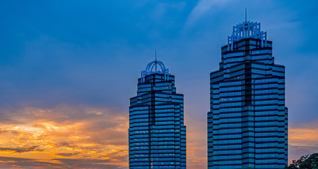 Two blue glass office towers at sunrise