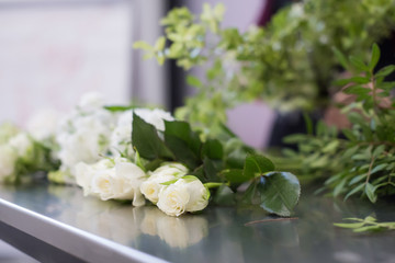 Beautiful white flowers and florist's tools lie on a glossy gray table. Concept of master class for making beautiful flower bouquets