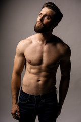 Fototapeta premium Photo of smiling mature man standing isolated over grey wall background naked. Looking in the left high corner.