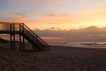 Fototapeta na wymiar Early morning at the Atlantic beach.Marine background with wooden boardwalk and stairs to the beach and beautiful colorful sky before sunrise. Scenic seascape at the Pawleys Island,South Carolina,USA.
