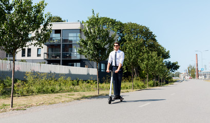 business and people and concept - young businessman riding electric scooter outdoors