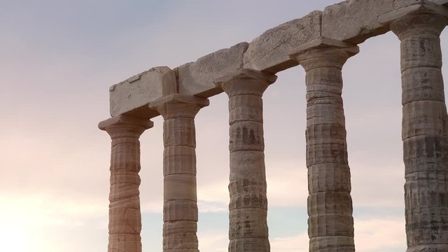 Temple of Poseidon on Cape Sounion above Aegean sea, Greece. Amazing colorful sunset. Ancient stone ruins of iconic construction with columns and stairs. Mythology of hellenic civilization. Zoom out